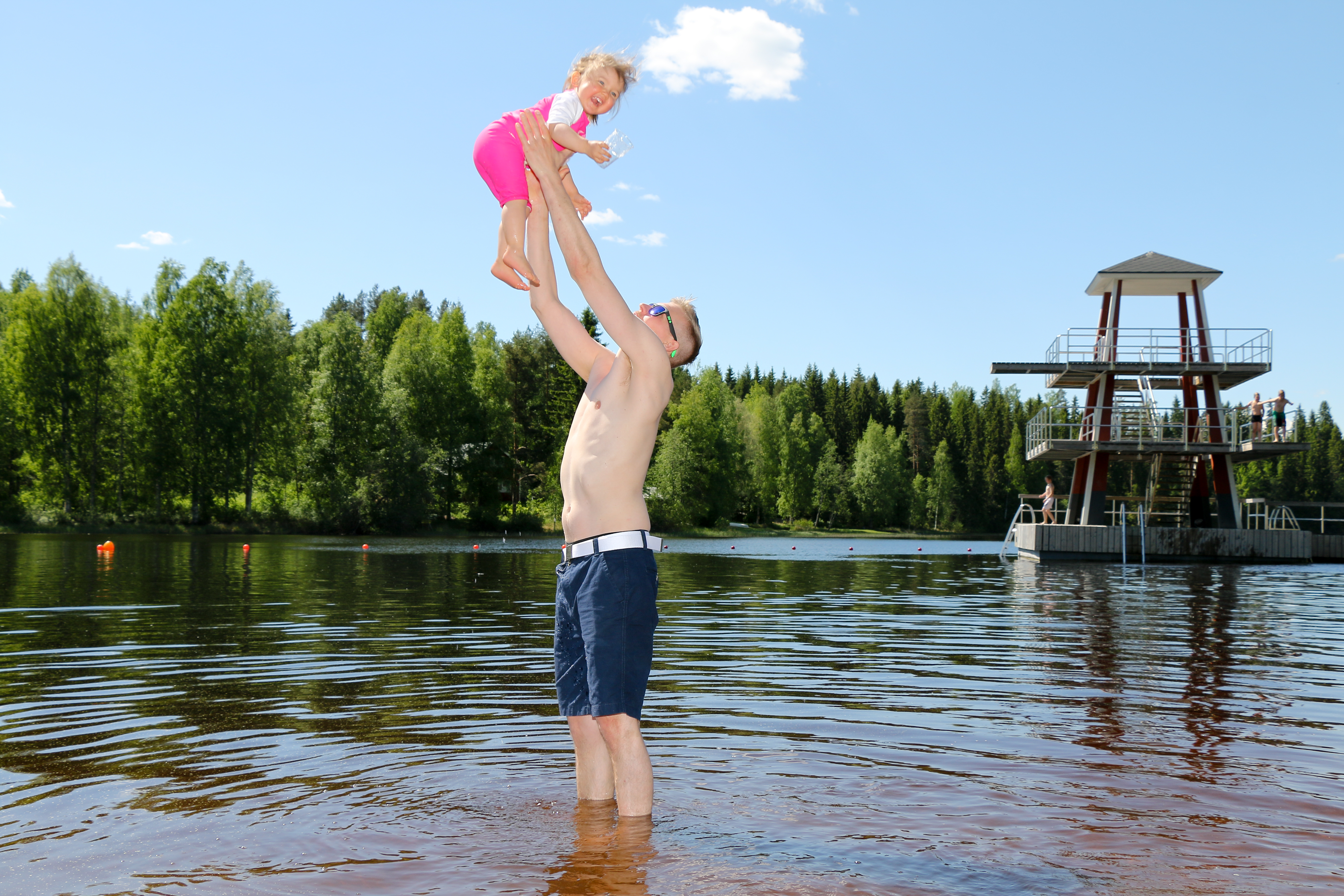 Isä nostaa tytärtään ilmaan vedessä